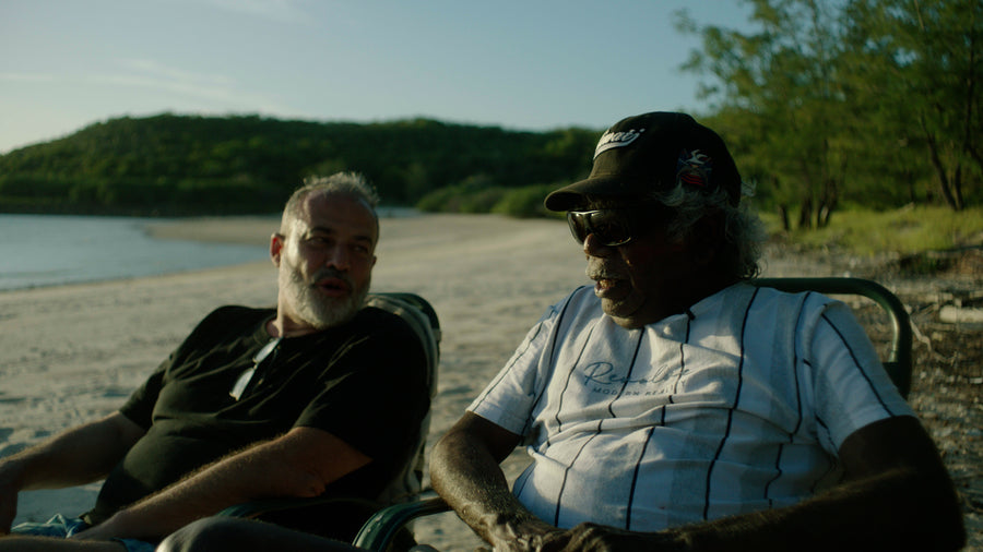 Two men resting on the shore beside the water