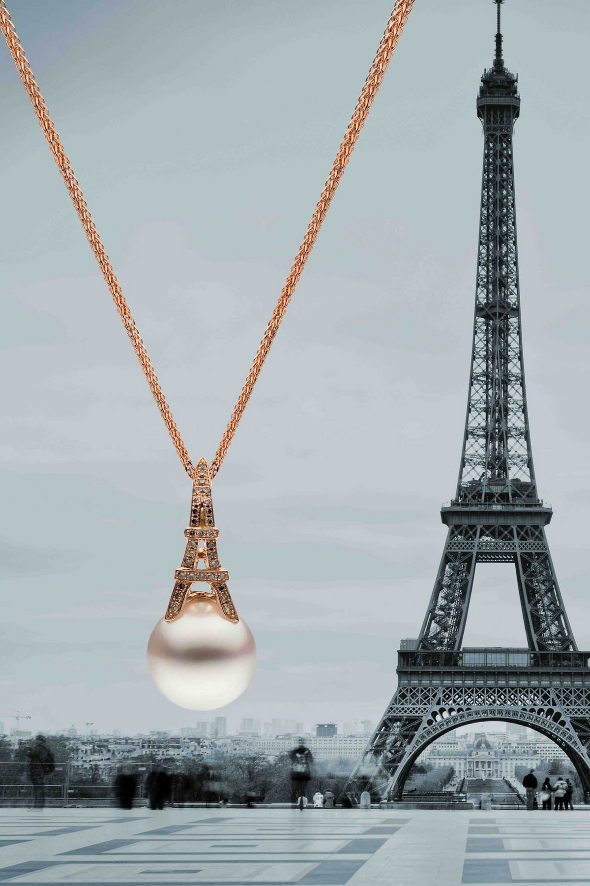 Metropolitan pendant with a South Sea pearl beneath a miniature Eiffel Tower, with the Eiffel Tower behind